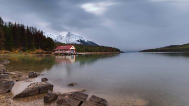 Jasper, Kanada-1 Ekim 2021 1928 tarihli Maligne Gölü kayıkhanesinin Kraliçe Elizabeth Dağları 'ndaki kozalaklı ormanlar tarafından korunan tarihi görüntüsü..