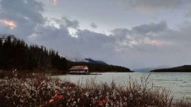 Jasper, Kanada - 3 Ekim 2021 1928 tarihli Maligne Gölü kayıkhanesi üzerine bulutlu ve rüzgarlı bir şafak inşa edildi..