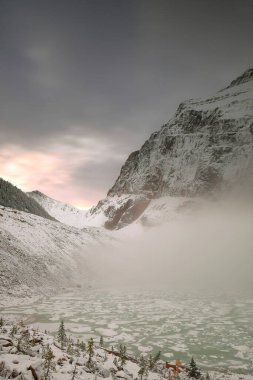 Yoğun sis, Edith Cavell Dağı 'nın kuzey yamacını kaplar ve eteklerinde yakınlardaki Cavell ve Angel Buzdağlarından düşen buzdağlarıyla dolu bir mağara vardır. Jasper NP-Alberta-Kanada.
