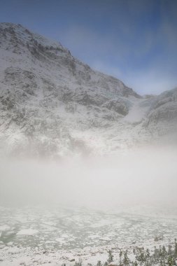 Yoğun sis, Edith Cavell Dağı 'nın kuzey yamacını kaplar ve eteklerinde yakınlardaki Cavell ve Angel Buzdağlarından düşen buzdağlarıyla dolu bir mağara vardır. Jasper NP-Alberta-Kanada.