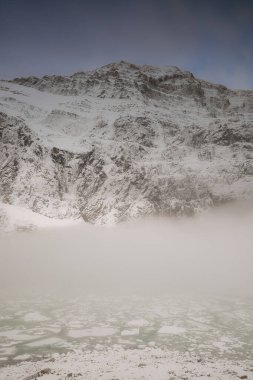 Yoğun sis, Edith Cavell Dağı 'nın kuzey yamacını kaplar ve eteklerinde yakınlardaki Cavell ve Angel Buzdağlarından düşen buzdağlarıyla dolu bir mağara vardır. Jasper NP-Alberta-Kanada.