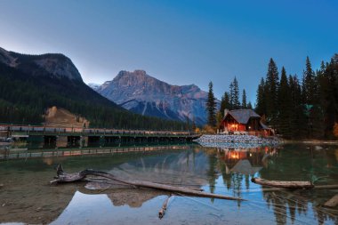 Emerald Gölü 'nün güneybatı ucunda bulutsuz bir alacakaranlık ve Emerald Lodge yarımadasına giden yol köprüsü. Zümrüt-Michael arka planda. Field, Yoho NP, British Columbia, Kanada.