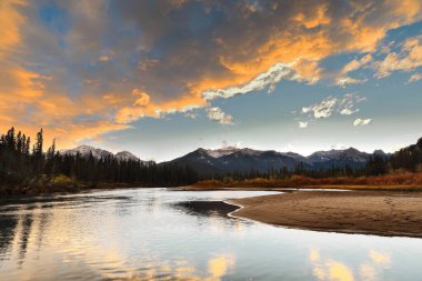 Bow River Vadisi 'nin karlı tepelerinde, Icefields Parkway' den geçen renkli akşam bulutları. Yavaş akıntısı, kırmızımsı çalılar ve kozalaklı ağaçlarla kaplı kum kütleleriyle kaplı. Banff NP-AB-Kanada.