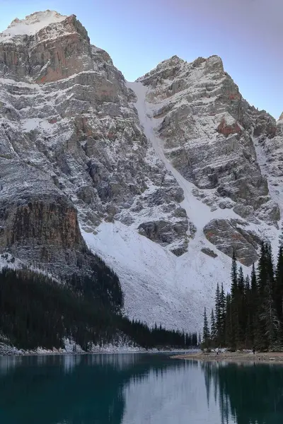 On Tepe Vadisi 'ndeki Moraine Gölü' nün zümrüt yeşili yansıtıcı suları mavi gökyüzünün altında bulutsuz bir gündoğumunda kuzey kıyısından güney batıya doğru görüldü. Banff NP-Alberta-Kanada.