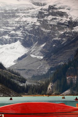 Victoria Dağı eteğindeki etkileyici Victoria Asma Buzulu zümrüt-turkuaz Louise Gölü 'nde yüzen ikonik kırmızı kanoların arka planında yer alıyor. Banff NP-Alberta-Kanada.