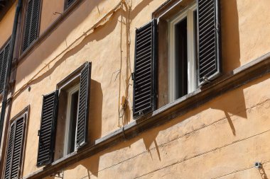 Kahverengi boyalı, hoparlörlü pencereler. Via dell 'Opio nel Corso' daki üç katlı Rönesans tarzı evin şeftali rengi cephesinde açık ve kapalı. Montepulciano-Toskana-İtalya.