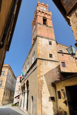 Comunale-Town Sarayı güneydoğu köşesi ve saat ve çan kulesi, güney cephesi ve girişi ile Corso il Rossellino Caddesi 'nden görülen Pio II Meydanı' na bakıyor. Pienza-Toskana-İtalya.