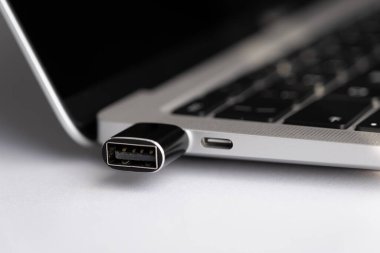 Bağlantı arayüzüne takılı USB tipi c adaptörü olan bir dizüstü bilgisayarda yan görünüm