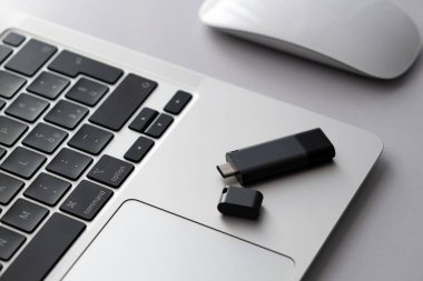 USB flaş bellek, klavyesinin önünde gri laptop çantasının üzerinde duruyor. USB tip-c çıktısına sahip sanal bellek depolama