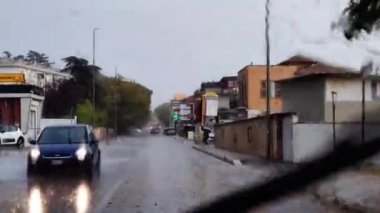Roma İtalya, 10 Ekim. 2022 yılı. Şiddetli yağmur damlalarıyla araba camından geçen yol trafiği. Yağmurda arabanın ön camından görülen trafik manzarası. Yağmurda sürüş.