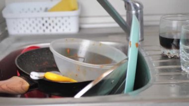 Lavabo kirli bulaşıklarla dolu. İhmal edilmiş bir sürü kirli kase ve kap kacak için yakın çekim. Dağınık bir mutfakta yemek pişirmenin sonucu.