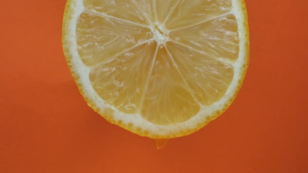 レモン汁はパルプから流れ オレンジの背景に滴 マクロビデオ スローモーション — ストック動画
