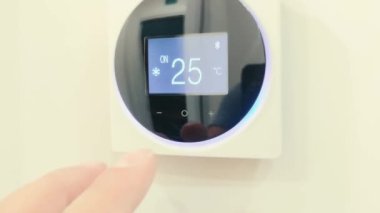 Adamın elini kapatıp düğmelere basıyor daire ve ofis için klima ve ısıtma kontrol paneli beyaz bir duvarda bulunuyor. Kapat.