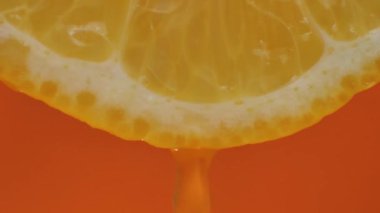 Limon suyu hamurdan akar ve turuncu arka planda damlalar, makro video, kelime hareketi.