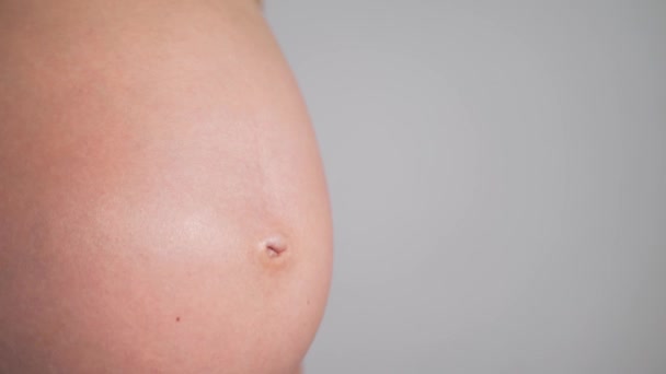 怀孕的女人健康怀孕母性生育概念阳光 孕妇的近视腹部 一个在等新生儿的女人 孕妇抱着肚子呆在室内 — 图库视频影像