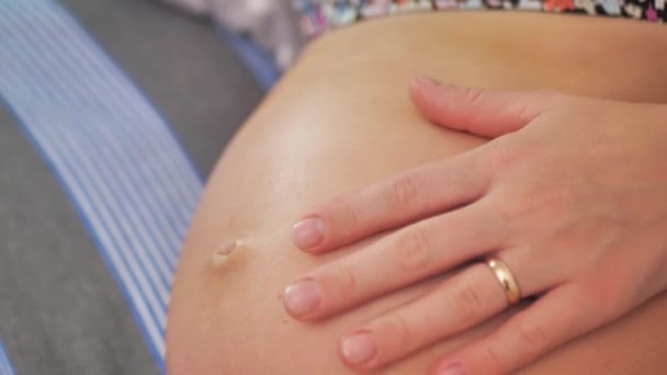 ソファに寝そべっている間にお腹に触れた妊婦のクローズアップ 子供を準備し期待する母親という概念 — ストック動画