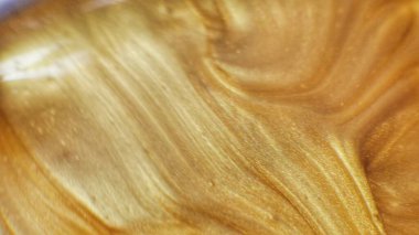 Parıltılı boya akışı. Erimiş altın dokusu. Yüzen mürekkep. Odaklanmamış sarı turuncu parlak sıvı hareketi. Soyut sanat arkaplanı.