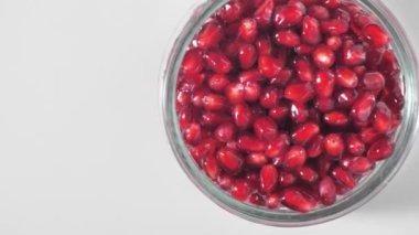 Beyaz arka planda şeffaf cam bir kaseye doldurulmuş nar tohumları. Harika kompozisyon, kavramsal el bombası çekimi, videoyu al.