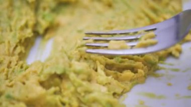 Yakın plan, çatalla avokado ezmek. Guacamole sosu hazırlama, avokado doğrama. Sağlıklı vejetaryen yemekleri pişirmek..