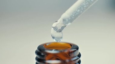 Masaj için kozmetik yağlı boru ve damlalar kahverengi bir şişeye akıyor, yakın plan..