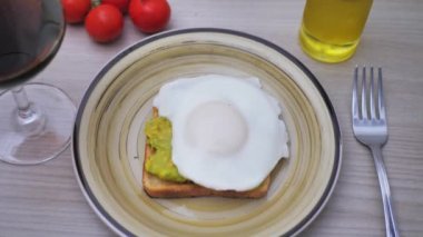 Kızarmış ekmeğin üstüne avokado püresi, üzerine baharat serpiştirilmiş yumurta.