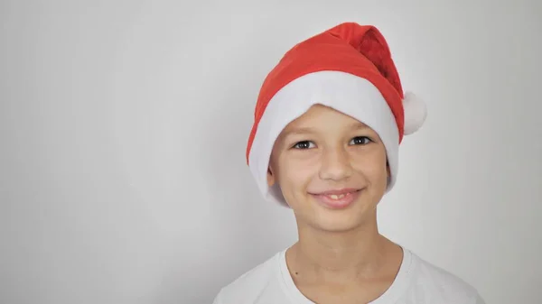 白いTシャツの子供と赤いサンタクロースの帽子 白い背景に隔離されたデザインやテキストのための空のコピースペース クリスマスと新年 — ストック写真