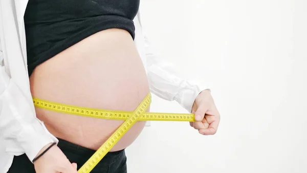 美しい妊娠中の女性は白で隔離され 彼女の胃を測定します — ストック写真