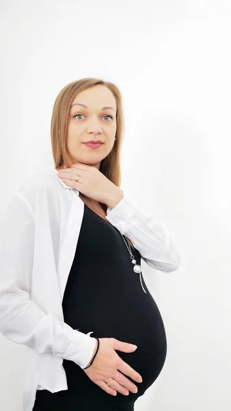 一个年轻孕妇在白色背景上的肖像 把他的手放在他肿胀的肚子上 爱的概念 具有复制空间的横向 — 图库照片
