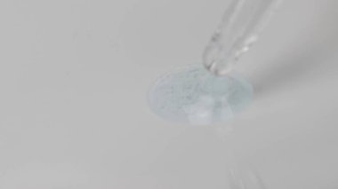 Gri ölçekli makro jel, farklı boyutlarda küçük kabarcıklar bir pipetten akıyor. Hyaluronik asit bileşimi içeren soyut cilt bakımı jeli.