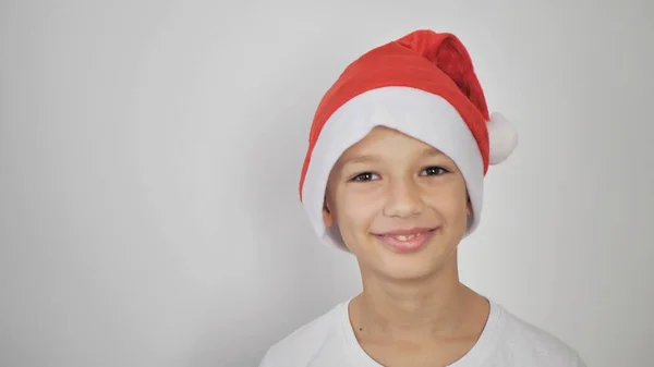 白いTシャツの子供と赤いサンタクロースの帽子 白い背景に隔離されたデザインやテキストのための空のコピースペース クリスマスと新年 — ストック写真