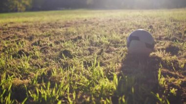 A boy plays soccer with a ball. Childrens feet hit the ball in slow motion, the beauty of the suns rays