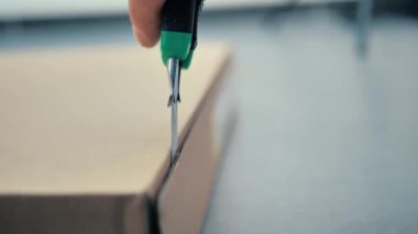 bir kişi paketi bir araçla açar.