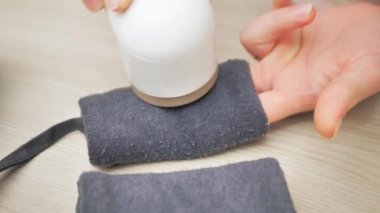 Kadın, modern el yapımı elektrikli kumaş traş makinesi kullanarak kazaktan hap çıkarıyor. Kıyafet bakım konsepti