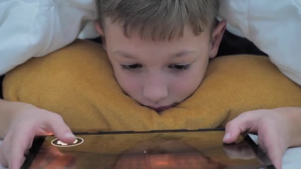 Mały Chłopiec Bawi Się Tablecie Leżąc Pod Kocem Oglądanie Kreskówek — Wideo stockowe