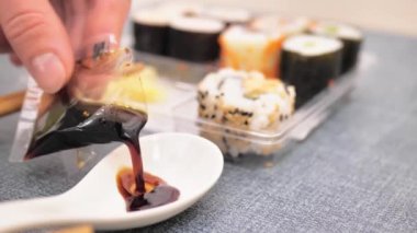 Kadın elleri paketten bir kaba soya sosu döker..