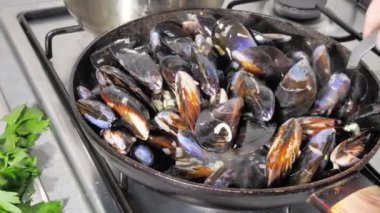 Midye ve istiridye sokak yemekleri. Sıcak sosla büyük bir tavada deniz ürünleri pişirip karıştırmak. Akdeniz mutfağı. Kızgın bir tencerede kızarırlar..