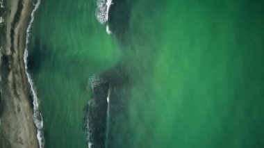 Oldukça sakin deniz suyu, duvarın yakınındaki taşları yıkıyor, liman sığınağının etrafını koruyor. Üst aşağı manzara, güneşli bir günde güzel turkuaz su rengi. Alt kısmı şeffaf.