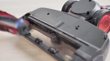 Ev işleri ve teknoloji konsepti. Robot elektrik süpürgesinin bakımı ve bakımı. Temizlik, onarım, yedek parça. Evde robot temizleyiciyi tamir eden adam. Akıllı ev fonksiyonları, tam otomatik.