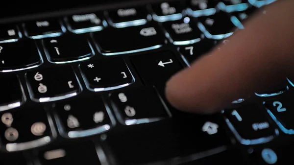 Finger pressing an enter key. Computer user hitting the enter key, up close. Confirmation, sending a message.