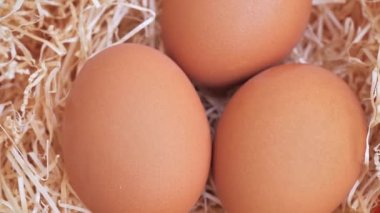 close up of three spinning eggs on hay.