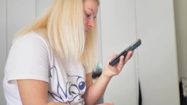 Rahat sarışın kadın akıllı telefon kullanarak sosyal medyada geziniyor, haberleri kontrol ediyor, mobil oyunlar oynuyor ya da rahat bir koltukta oturmuş mesaj yazıyor. Milenyum bayanı evinde cep telefonuyla vakit geçiriyor..