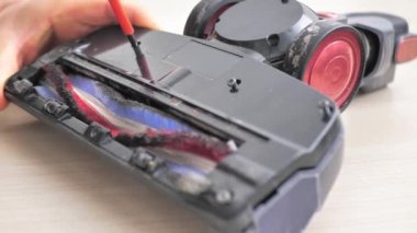 Ev işleri ve teknoloji konsepti. Robot elektrik süpürgesinin bakımı ve bakımı. Temizlik, onarım, yedek parça. Evde robot temizleyiciyi tamir eden adam. Akıllı ev fonksiyonları, tam otomatik.