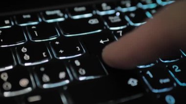 Finger pressing an enter key. Computer user hitting the enter key, up close. Confirmation, sending a message.