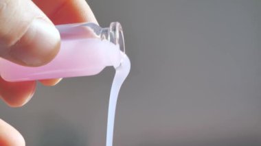 Pembe renkli sıvı su beyaz zemin üzerine yayılıyor.