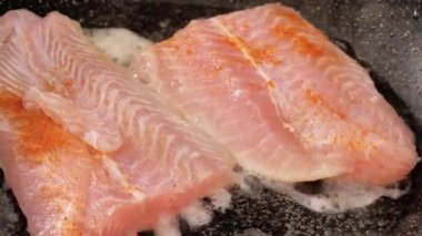 Grilled salmon fish in a pan on a flaming grill.