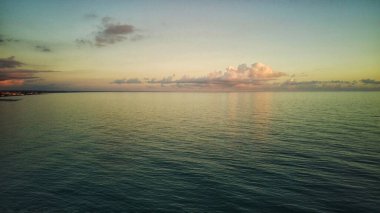 Golden sunset on a beach - slow motion of foamy waves rolling towards white sand beach under low the sun light.