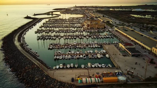 stock image Top down aerial view above luxury yachts parked on turquoise ocean water marina, at dusk.