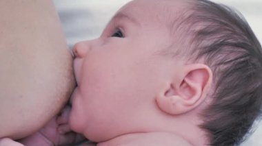 Kadın yeni doğmuş bebeği emziriyor. Anne, yeni doğmuş bebeği yatakta emziriyor. Emzirme kavramı. Bebek yiyen anne sütü. Bebeği emziren ve besleyen genç bir kadın. Emzirme bebeği kavramı.