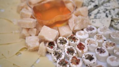 Preparation of a cheese plate from hard cheeses Camembert, Brie, Parmesan, Dutch cheese, honey. Appetizer for gourmets. Assortment of different Spanish French Italian snacks.