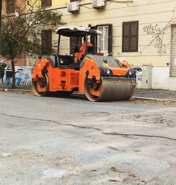 Workers level the newly laid asphalt on a damaged road with a mini roller compactor